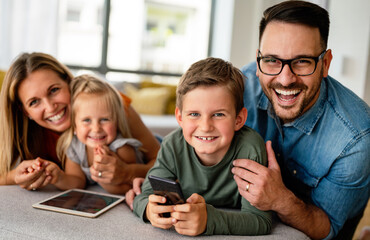 Happy young family having fun time at home. Parents with children using tablet