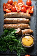Fresh mouth-watering kupaty with tomatoes, herbs, mustard sauce on a dark background. 
