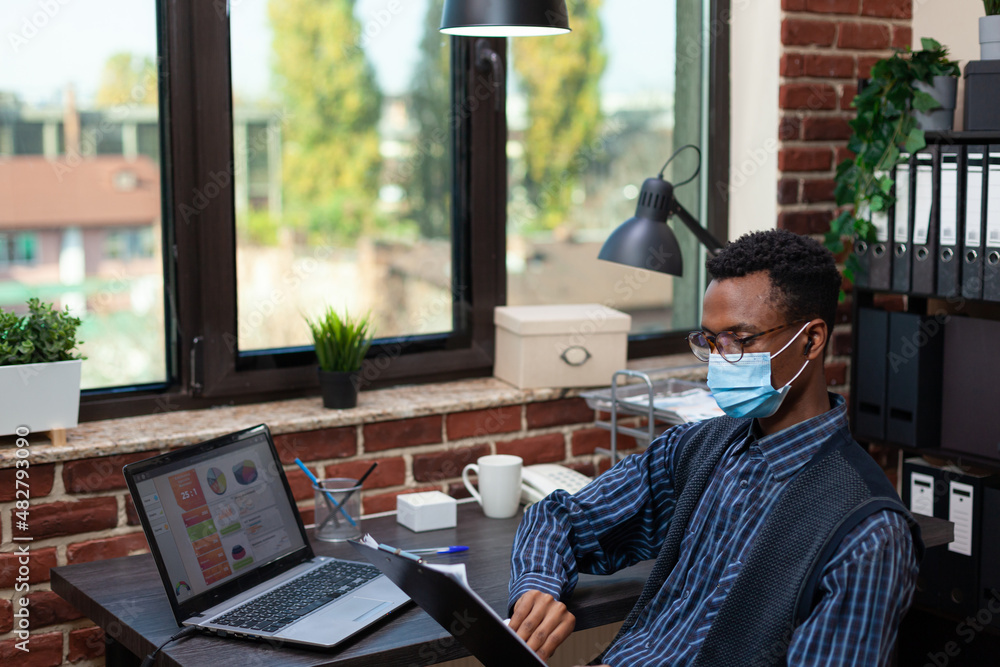 Aufkleber startup employee in covid isolation holding clipboard with bussiness charts sitting at desk comparin