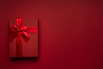Red gift box with red ribbon on a red background minimalism