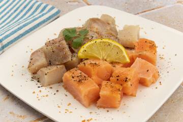 cut salmon and coalfish on a white background with parsley and lemon on a table