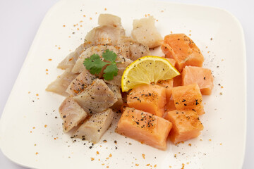 cut salmon and coalfish on a white background with parsley and lemon