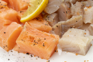 cut salmon and coalfish on a white background with parsley and lemon