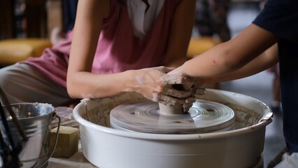 Fototapeta na wymiar Art master teacher making pottery workshop for kids and preschoolers in art studio, rounding pottery spot.