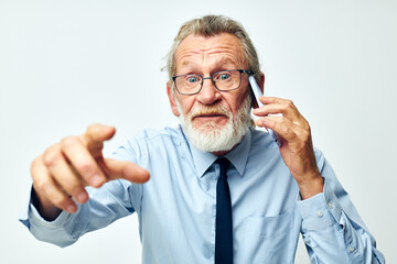 old man with the phone shows to the camera in the studio on a white background