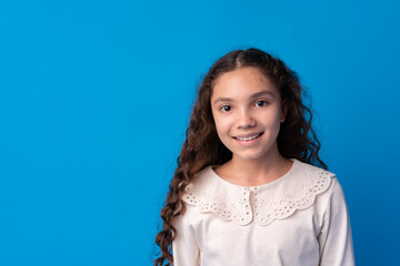 Portrait of a little smiling girl preteen on blue background