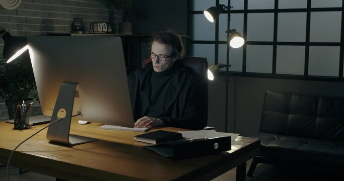 Young man using computer and laptop in dark room