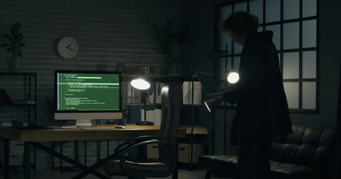 Programmer using laptop in dark room