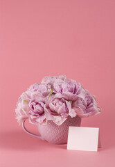 Violet tulips in vase with blank greeting card. Place for text. Mock up. Tulips in vase on pink background