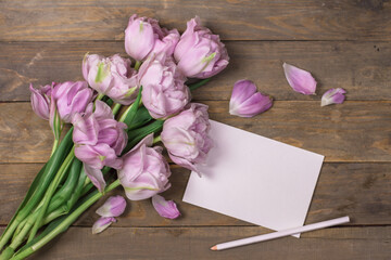 Mockup white greeting card with tulip on wooden background.