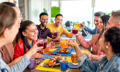 multiracial group of people sitting in a table bar restaurant enjoying english brunch breakfast together talking and having fun laughing. friends gathering in a irish pub indoor conviviality concept.