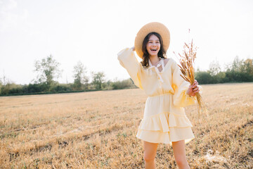 Portrait of a laughing Caucasian young brunette. girl in yellow summer dress and straw hat with a...