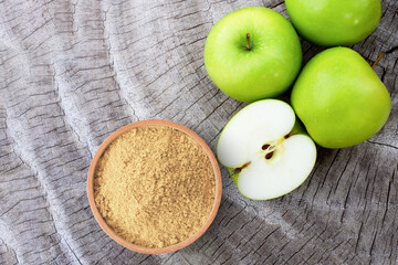 Apple pectin fiber powder in wooden bowl and fresh green apple on wooden table background. Top view. Flat lay.