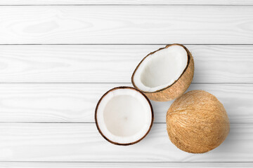 Coconut fruit and half slices isolated on wooden table background. Top view. Flat lay.