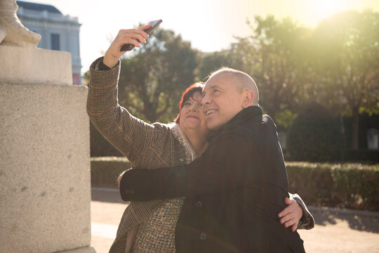 senior caucasian couple woman and man sitting in a park taking a picture