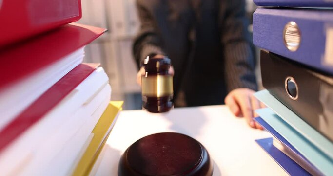 Judge knocking with gavel on table with lot of folders with documents closeup 4k movie