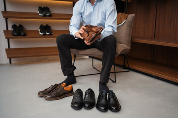 Young European man with dark hair brings wardrobe order puts everything in its place. Closet organized. Man chooses clothes. Capsule wardrobe for men.