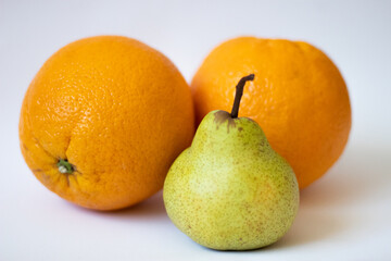 One pear and two oranges on a white isolated background