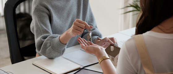 Fototapeta premium real estate agent holding house key to his client after signing contract agreement in office,concept for real estate, moving home or renting property