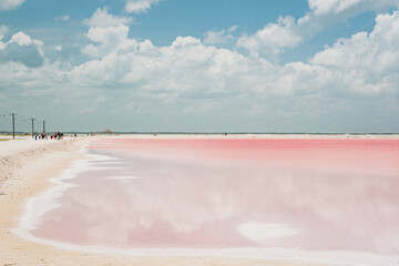 Pink lake with white salt near the shore. In the background, a salt factory against a blue sky. Las Coloradas, Yucatan, Mexico
