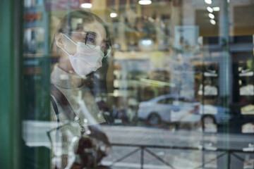 Young asian woman wearing face mask looking at a shoe shop showcase.