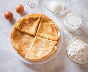Top view of two raw brown egg, flour, milk, sugar and whisk as ingredients of batter or dough pancakes on marble grey amd white surface