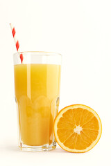 Glass of orange juice with colored paper tube and sliced orange on a white background