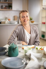 Beautiful woman enjoying in breakfast. Happy young woman eating sandwich at home...