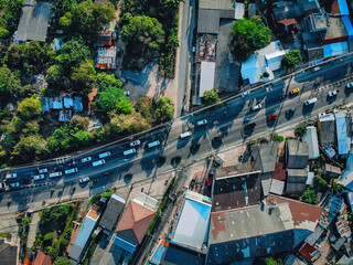 Top view of a wide road on the outskirts of the city with green trees, gardens and many cottages