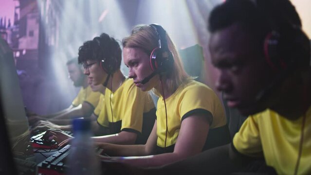 Female gamer esportsman with blond hair taking off headphones in anger after loosing match in video game with diverse teammates during esports championship