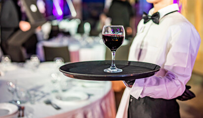 Waiter holding tray with red wine glass. Restaurant service