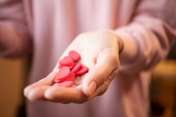 Hands holding red valentines on valentine's day. The girl's hands hold a lot of small hearts and fast-setting plasticine. The 14th of February. Holiday of love. The concept of giving love. give life