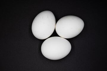 3 white eggs isolated on black background view from above