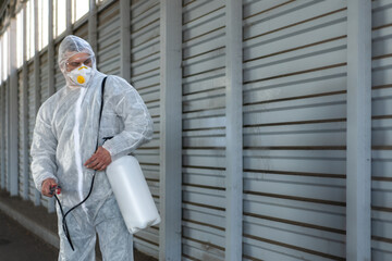 Worker wearing protective suit disinfection gear disinfect surface public place