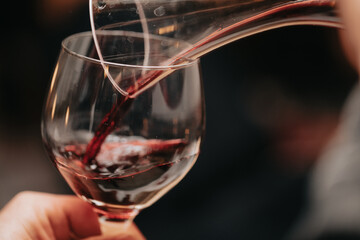 Glass of red wine in hand at a special event, a specific tasting of alcoholic beverages.