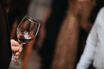 Glass of red wine in hand at a special event, a specific tasting of alcoholic beverages.