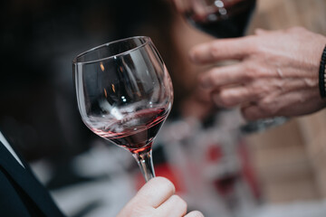 Glass of red wine in hand at a special event, a specific tasting of alcoholic beverages.