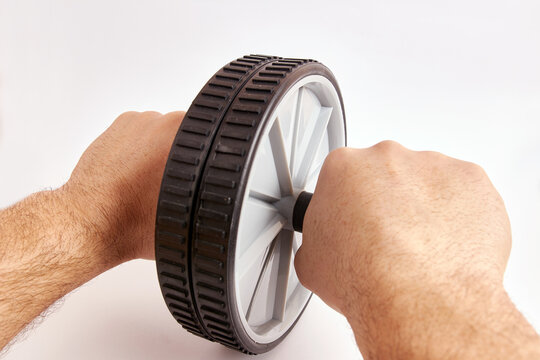 A man holds a gymnastic wheel with both hands to perform sports exercises.