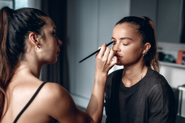 Make-up artist is doing make up to a young beautiful model, fashion