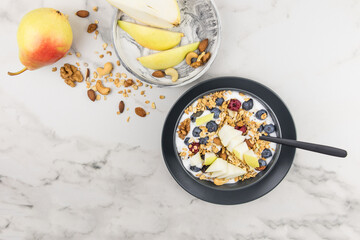 homemade muesli or granola made of oatmeal with nuts, berries and ripe pear. top view. marble...