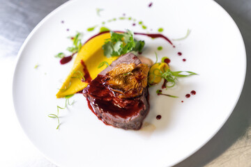 Beef cheek steak, caramelized in wine sauce with chanterelles in a white plate.