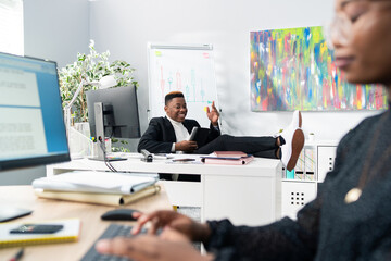 Obraz na płótnie Canvas The handsome boss of company sits comfortably in chair with feet on desk leans on it quickly comes up with a brilliant idea rises up holding the tablet in hand gestures