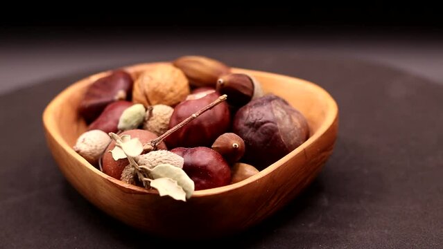 video of rotating olive wood bowl with various nuts, with selective focus on the foreground,