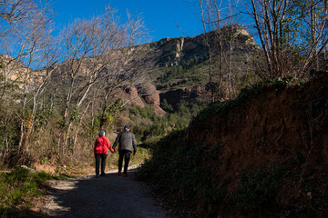 elderly couple walks outdoors trekking in the catalan landscape mountains and meadows in Sant Miquel del Fai in the Catalonia countryside. Rural catalunya and nature