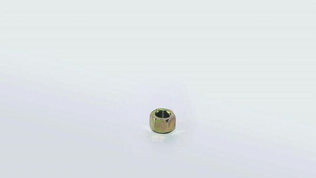 The metal nut rotates on a white background. Golden nut on a white background close-up