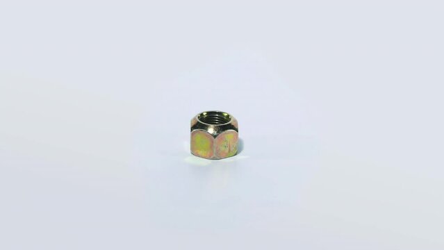 The metal nut rotates on a white background. Golden nut on a white background close-up