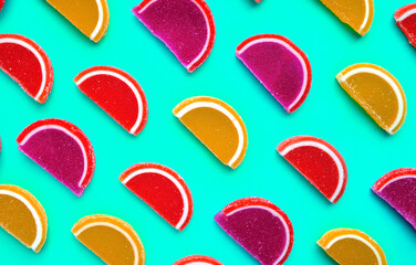 Colorful oval citrus jelly candies pattern on a turquoise background. Yellow, pink, red, orange round shaped marmalade