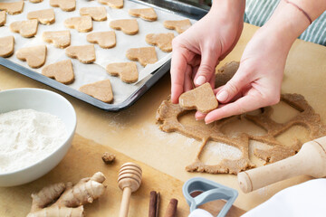 Women's hands lay out cookies on a baking sheet. The process of making holiday cookies for Valentine's Day. Home baking with love. Family care concept.