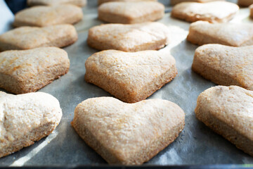 Ready-made heart-shaped cookies on a baking sheet. The process of making holiday cookies for Valentine's Day. Home baking with love. Selective focus.