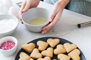 Creation of icing. Finished cookies need to be decorated. The process of making holiday cookies for Valentine's Day. Home baking with love. Horizontal orientation.